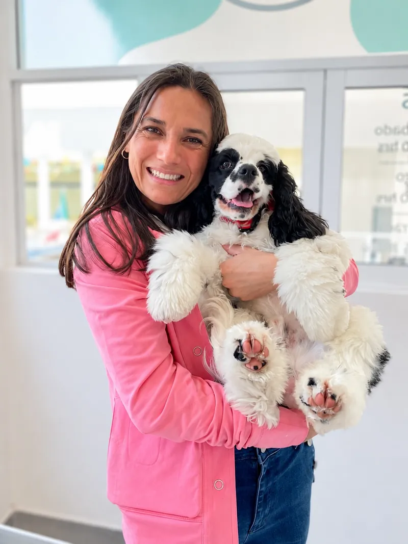 Tutora sonriente cargando a su perrito de pelo blanco y negro